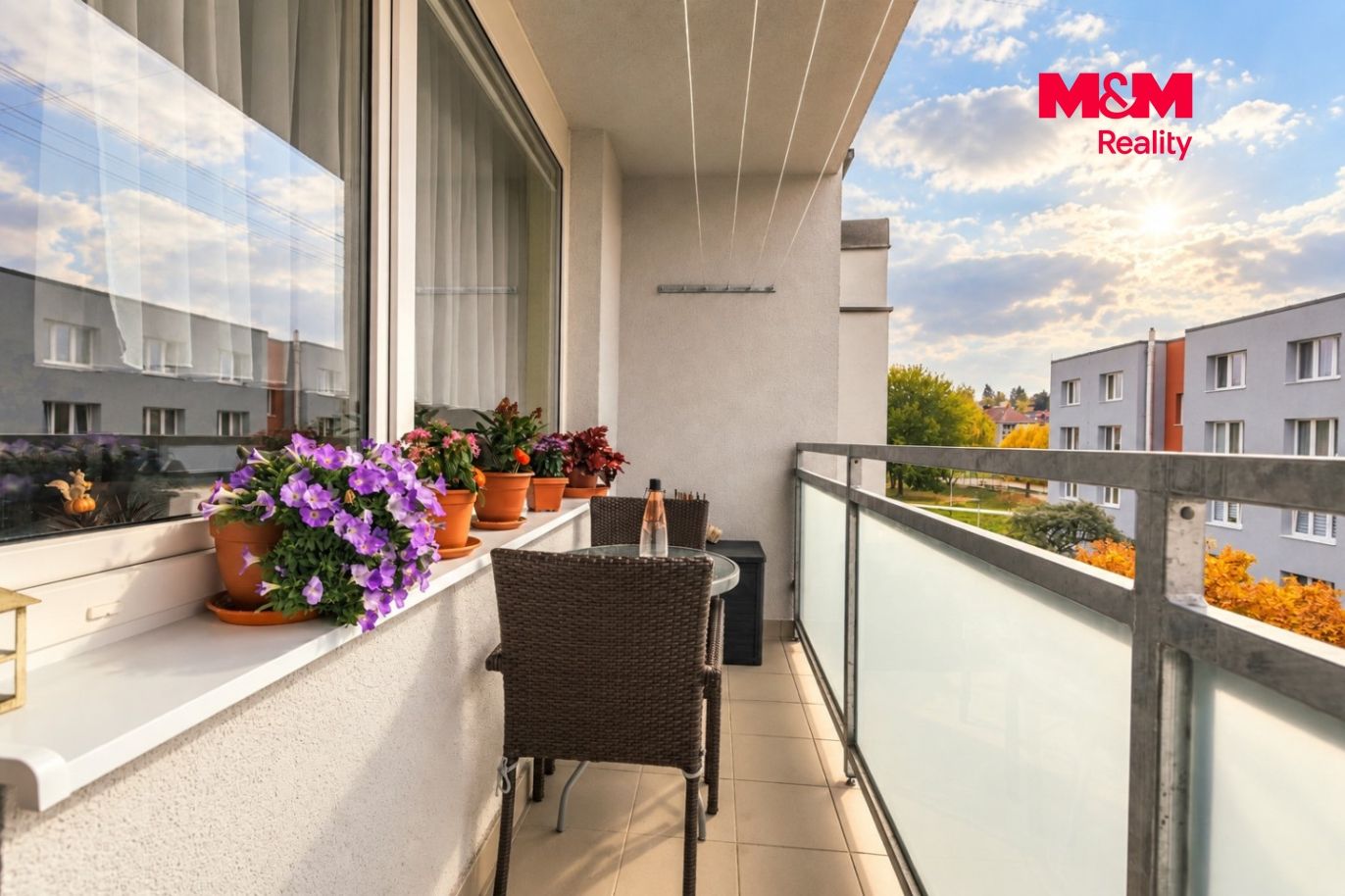 Slunný balkon s květinami a ratanovým posezením.jpg